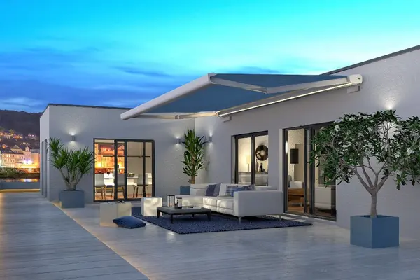 Moderne Terrasse mit Markise, stilvollen Gartenmöbeln und Pflanzen bei Sonnenuntergang.