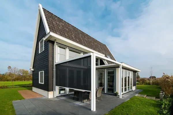 Modernes Einfamilienhaus mit Glas-Terrassenüberdachung und großem Garten im Grünen.