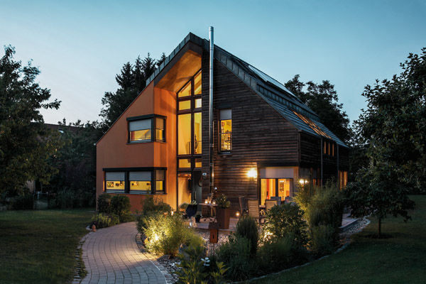 Modernes Einfamilienhaus mit großer Glasfront und Holzfassade im Abendlicht.